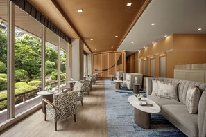 Een hotel lobby met een lange gang, een zithoek en uitzicht op een tuin.