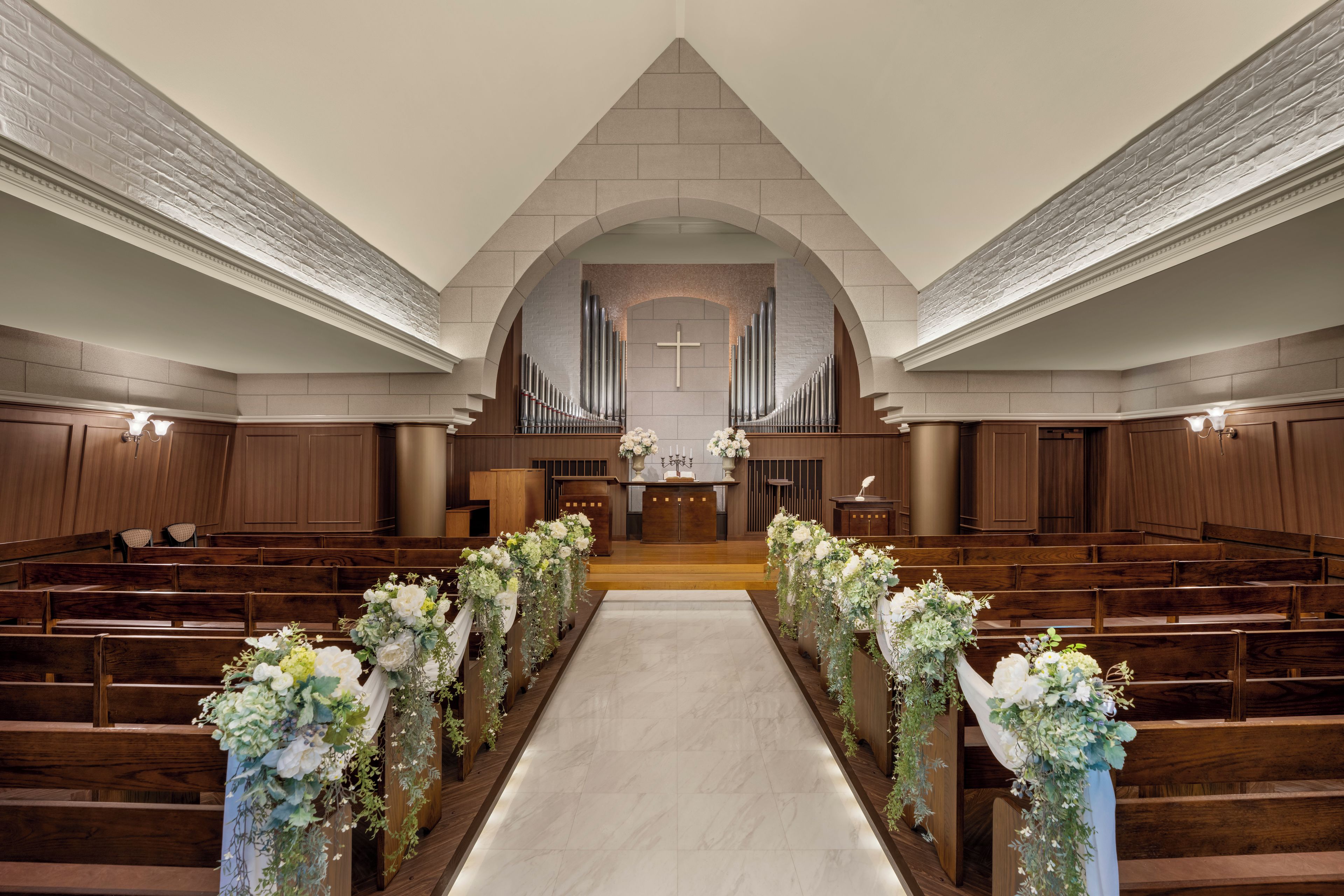 A church interior with wooden pews, a central aisle, and a pipe organ.
