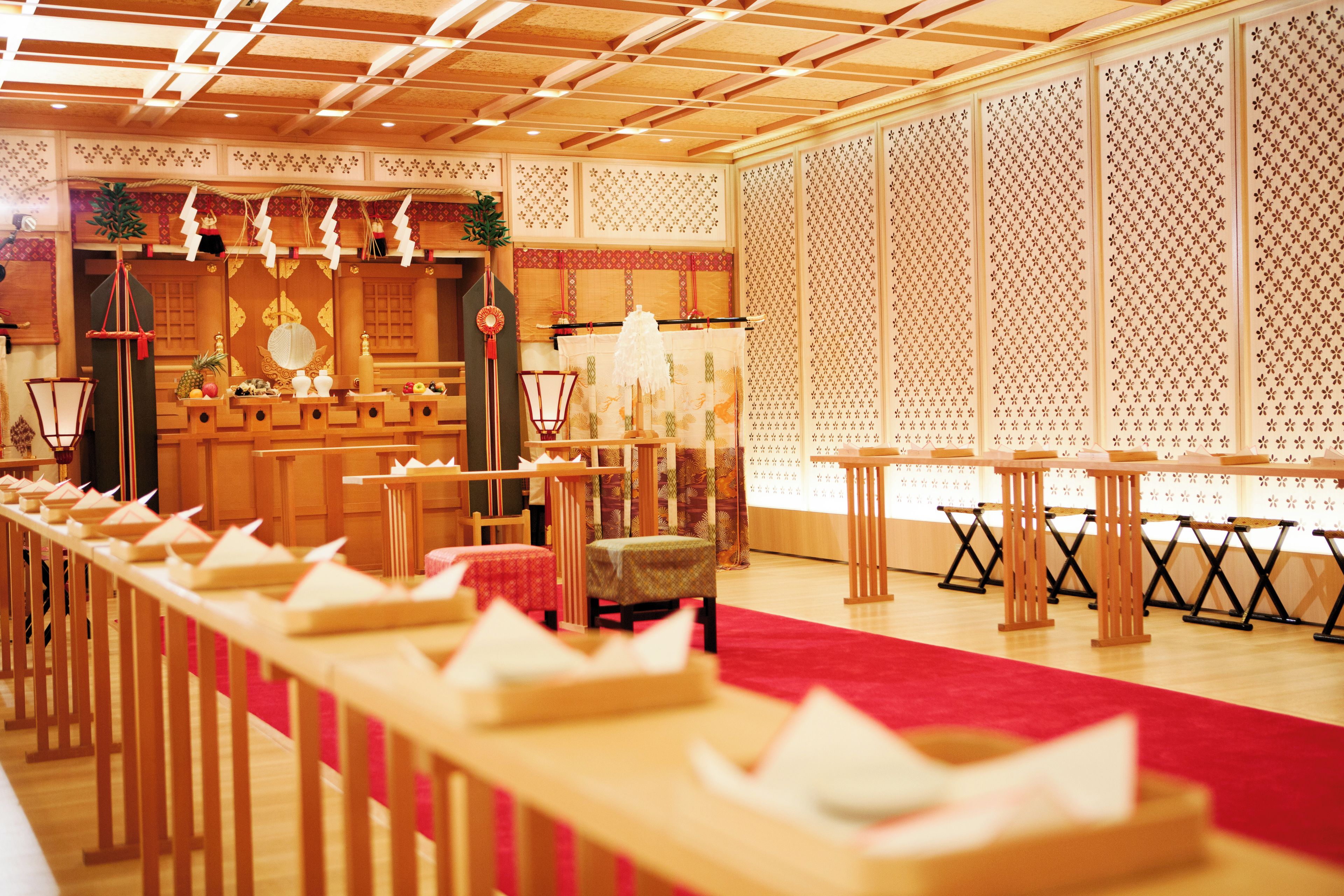A traditional Japanese-style room with tatami mats, low tables, and a red carpet.