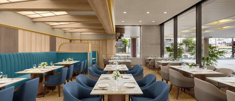 Ein modernes Restaurant mit Sitzgruppen, Tischen und Stühlen.