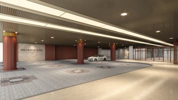 A spacious indoor area with a white car parked near a pillar, a sign reading 'ANA CROWNE PLAZA BY IHG Kochi', and a tiled floor.