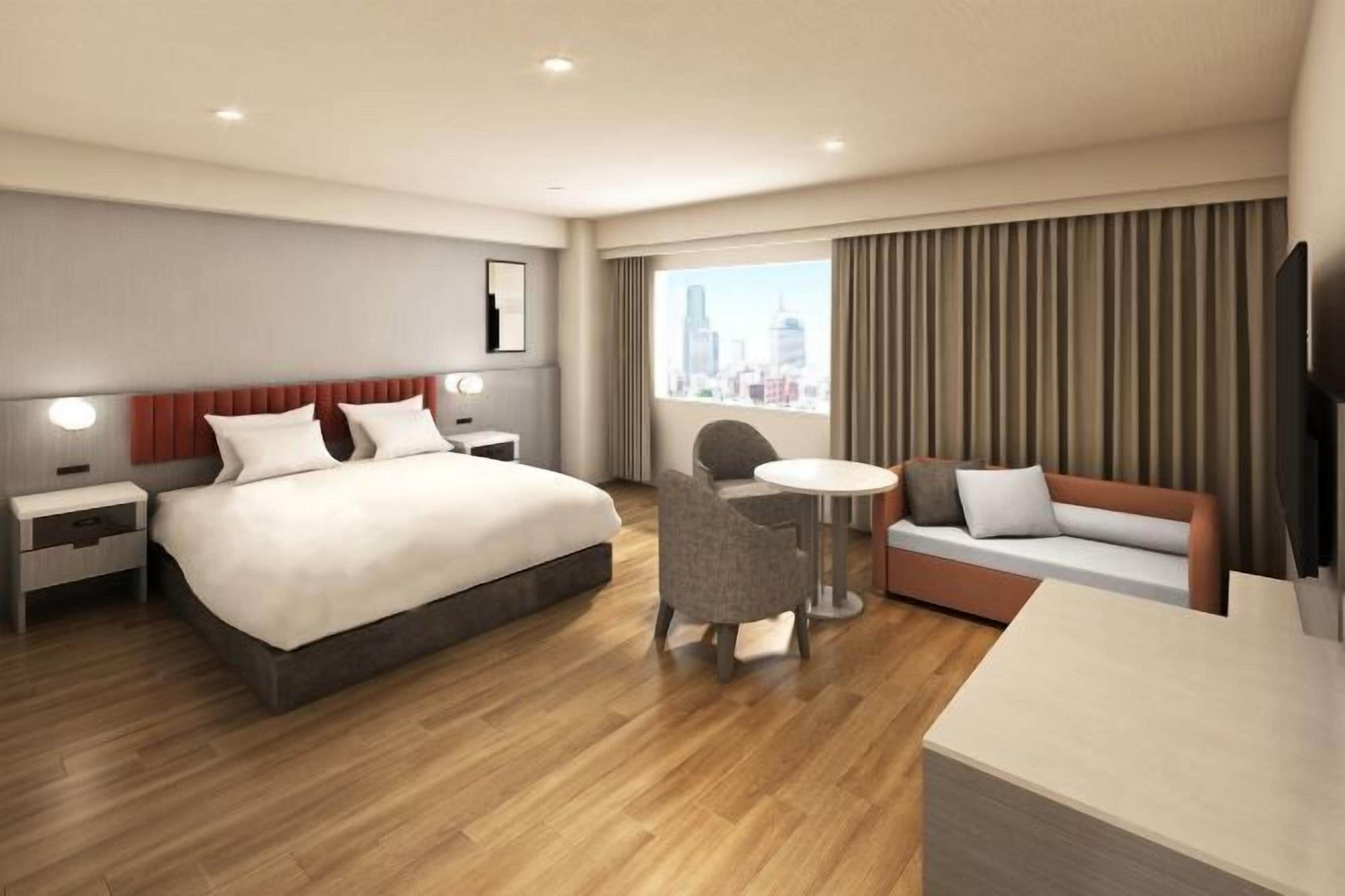 Ein Hotelzimmer mit einem großen Bett, einer Couch, einem kleinen Tisch und einem Fernseher.