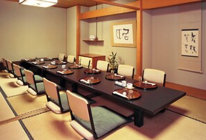 Une salle de conférence avec une longue table, des chaises et une petite plante.