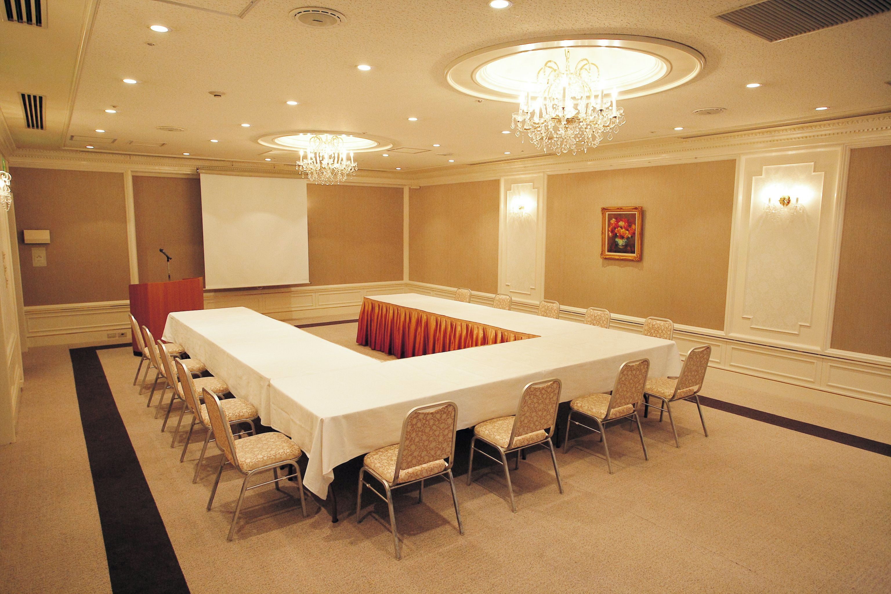 A conference room with a long table, chairs, a podium, and a whiteboard.