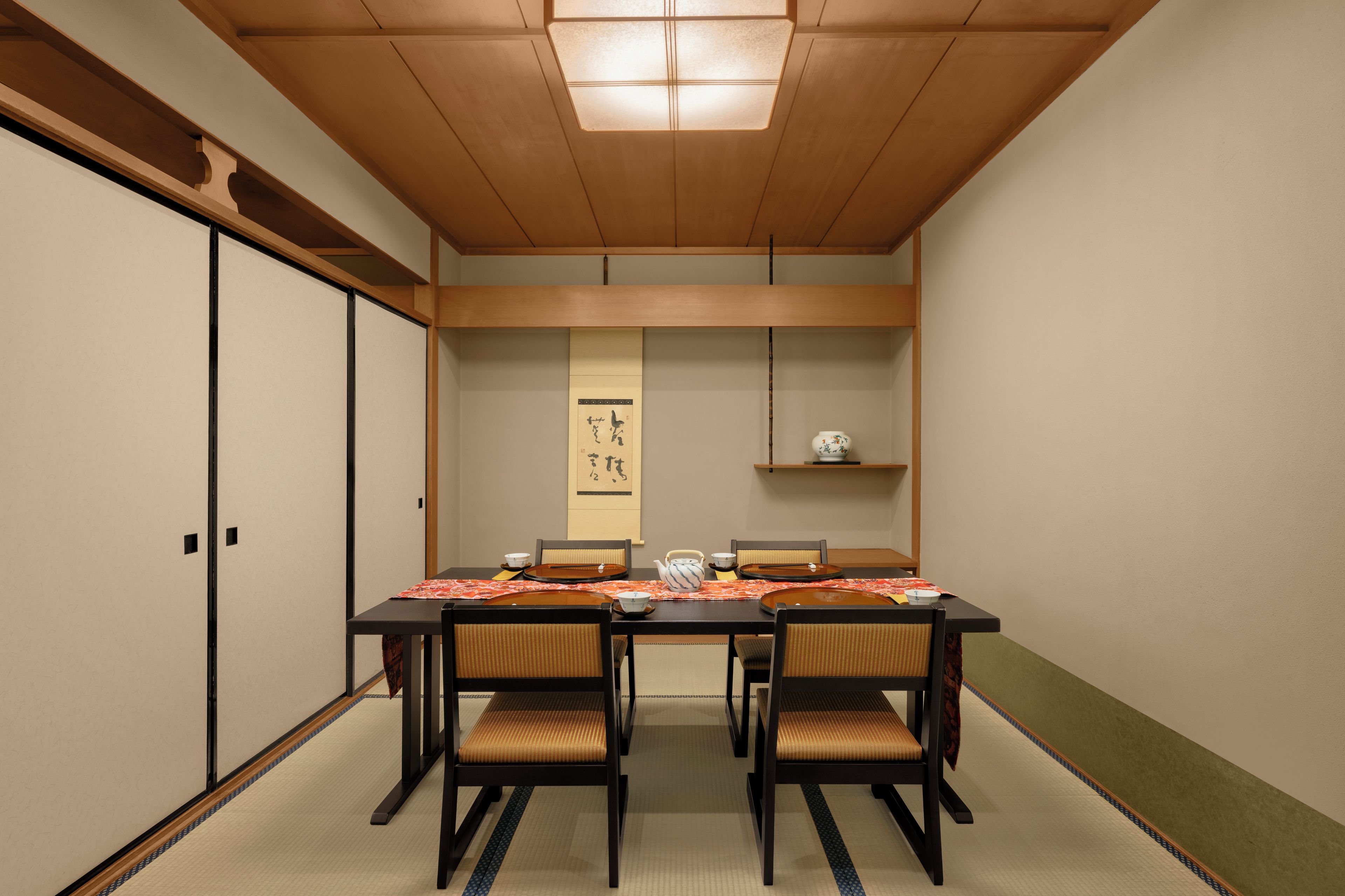 A traditional Japanese room with tatami flooring, a low table, and sliding doors.