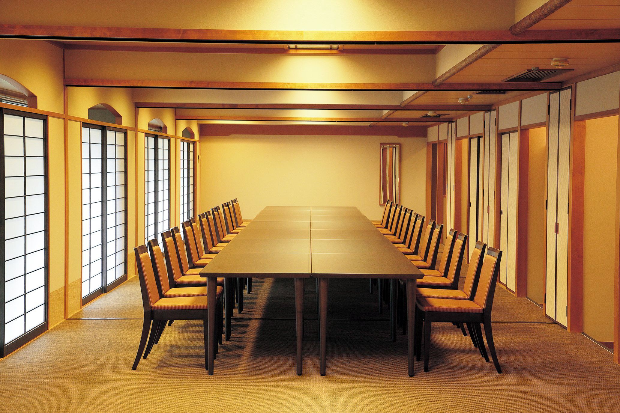 A conference room with a long table and chairs, wooden paneling, and large windows.