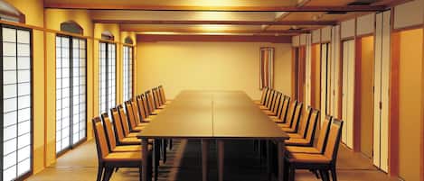 A conference room with a long table and chairs, wooden paneling, and large windows.