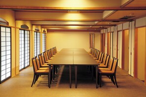 Ein Konferenzraum mit einem langen Tisch, Stühlen, Holzvertäfelung und großen Fenstern.