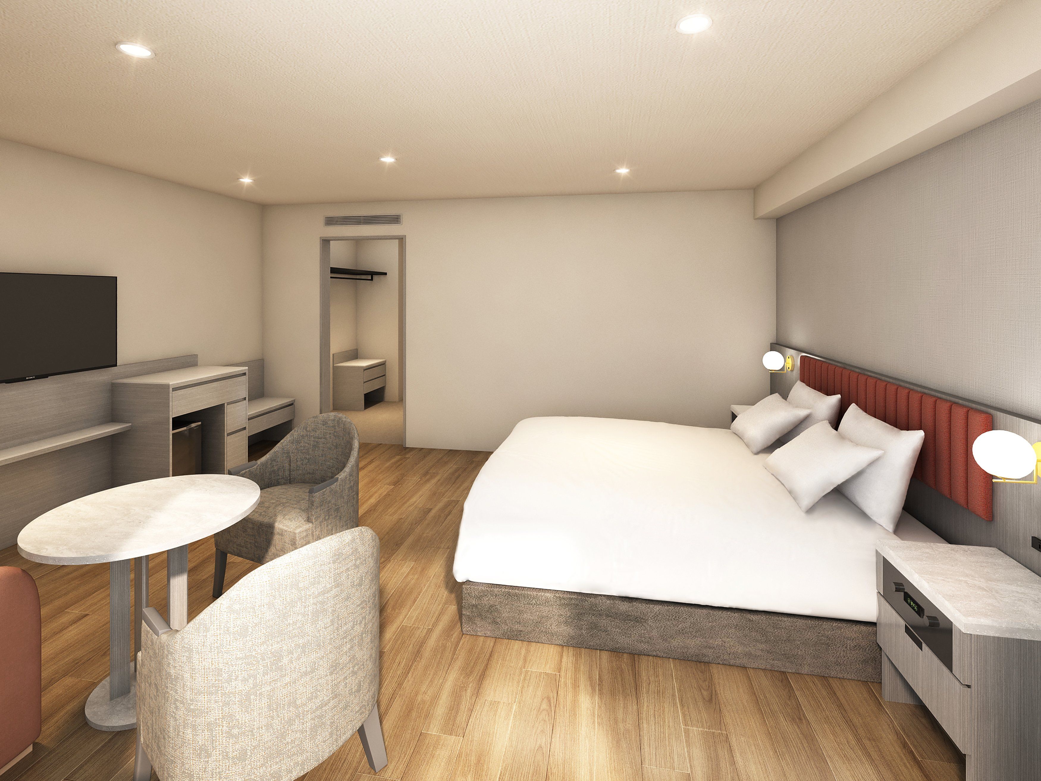 A modern hotel room with a bed, bedside table, chair, TV, and a small desk area.