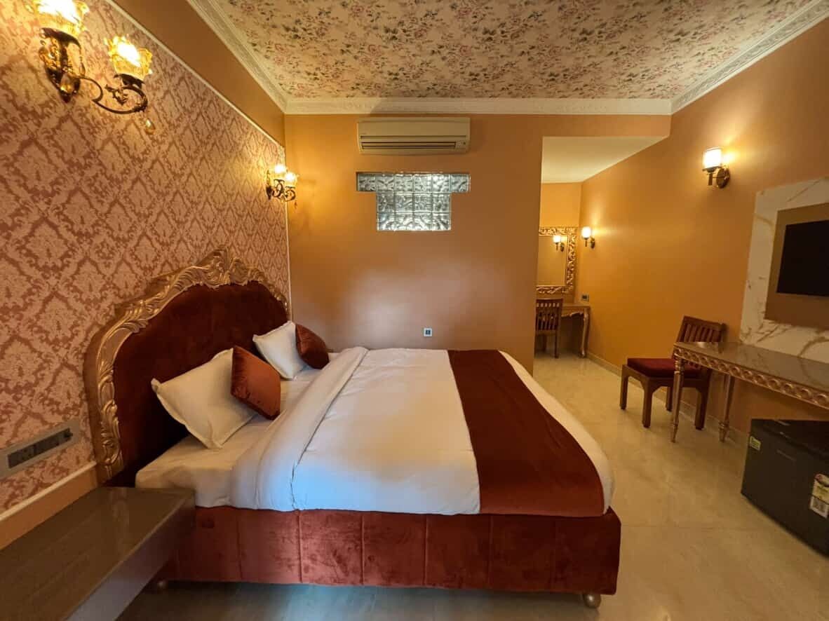 Habitación de hotel con una cama grande, un escritorio y una silla. Se ve una ventana con vistas al exterior.