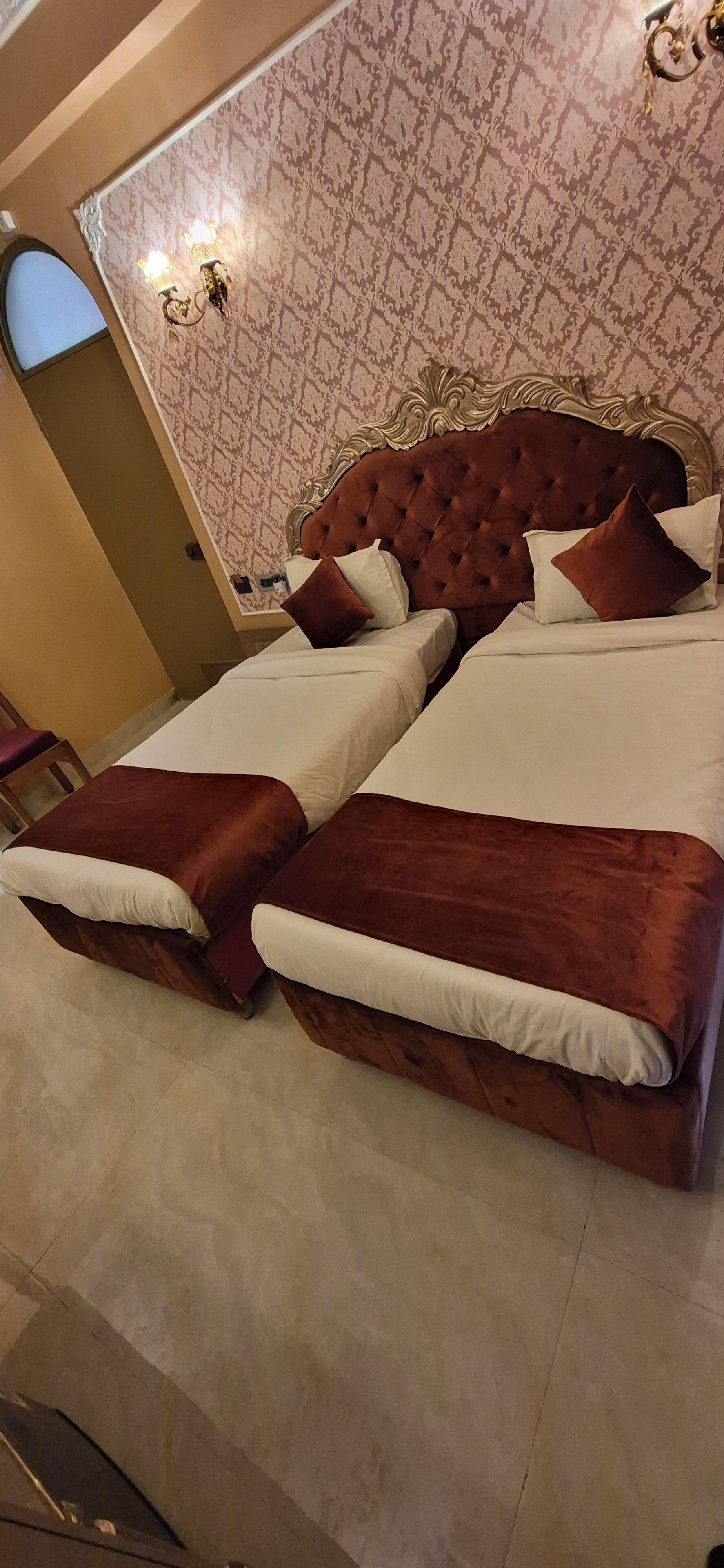 A double bed with a tufted headboard, two bedside tables, and a patterned wallpaper.