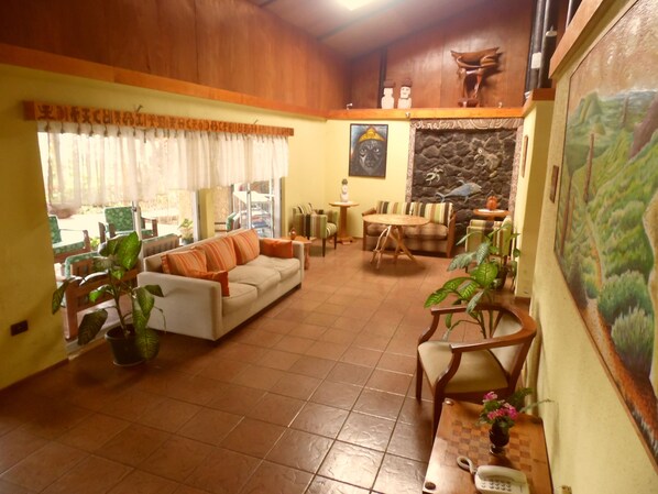 A spacious living area with a sofa, chairs, a coffee table, and a painting on the wall.
