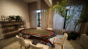 A room with a pool table, four chairs, a plant, and a bookshelf. - Hotel Euro Suíte Poços de Caldas By Nacional Inn (Poços de Caldas)