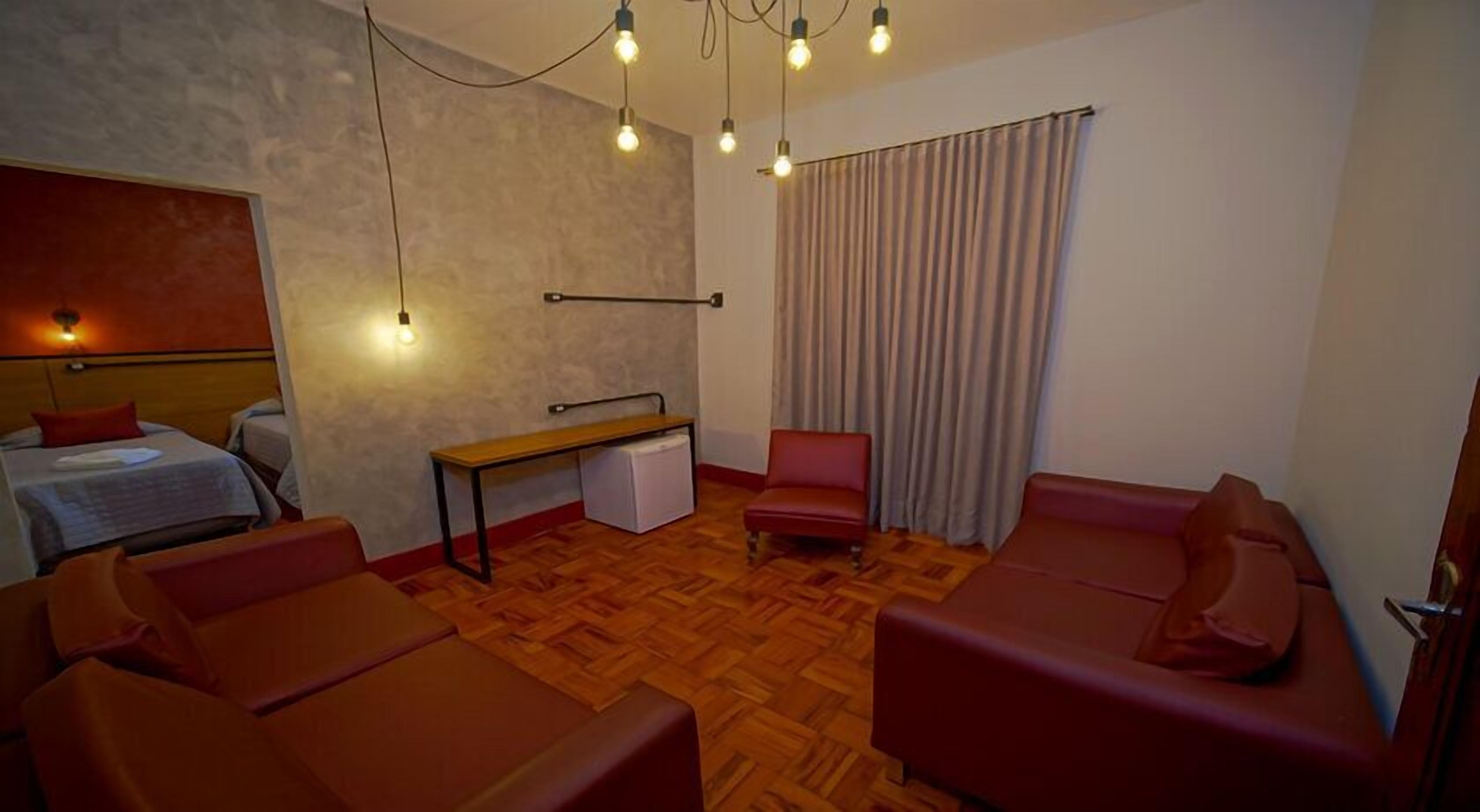 A hotel room with a bed, a desk, a chair, and a sofa.