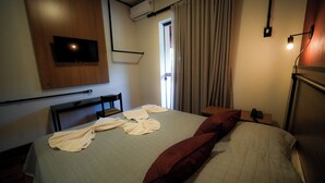 A hotel room with a bed, a TV mounted on the wall, a bedside table with a lamp, and a window with curtains. - Hotel Euro Suíte Poços de Caldas By Nacional Inn (Poços de Caldas)