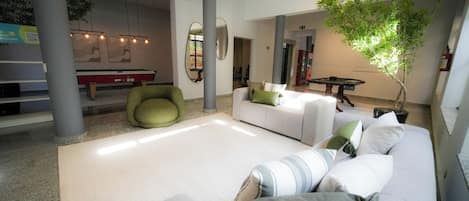Amplia sala de estar con sofá, sillones y mesa de billar.