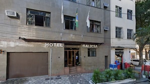 Un hôtel appelé « GALICIE », dont l’entrée est bien visible, et qui dispose d’un espace de stationnement avec des chaises et des tables.