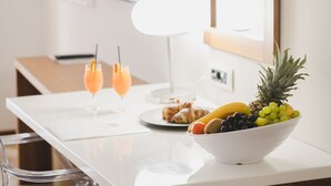 Ein Hotelzimmer mit einer weißen Minibar, einem flachbildfernseher an der Wand, einem spiegel mit Holzrahmen und einer Obstschale auf der Ablagefläche.