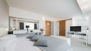 Ein modernes Hotelzimmer mit einem gro ßen Bett, einem Schreibtisch mit Fernseher, einem Spiegel und einer Holztür.