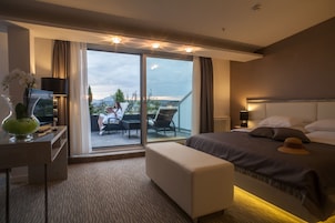 Una habitación de hotel con cama, escritorio, silla, una mesita y un balcón con vistas al exterior.