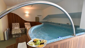Ein Whirlpool mit einer Fliesenverkleidung, Holzmöbeln und einer Obstplatte.
