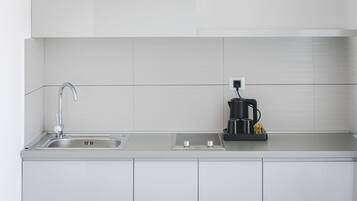 Une cuisine moderne dotée d’un évier en acier inoxydable, d’une machine à café et d’une prise électrique sur le plan de travail.