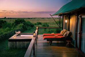 A wooden deck with a hot tub, lounge chairs, and a view of the savanna at dusk. - Olare Mara Kempinski Masai Mara (Maasai Mara)