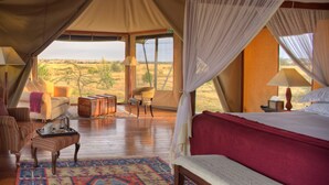 Una habitación con carpa, una cama, un sofá, una mesita y una silla.