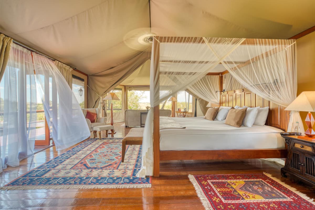 A spacious bedroom with a large bed, a canopy, and a view of the outdoors.