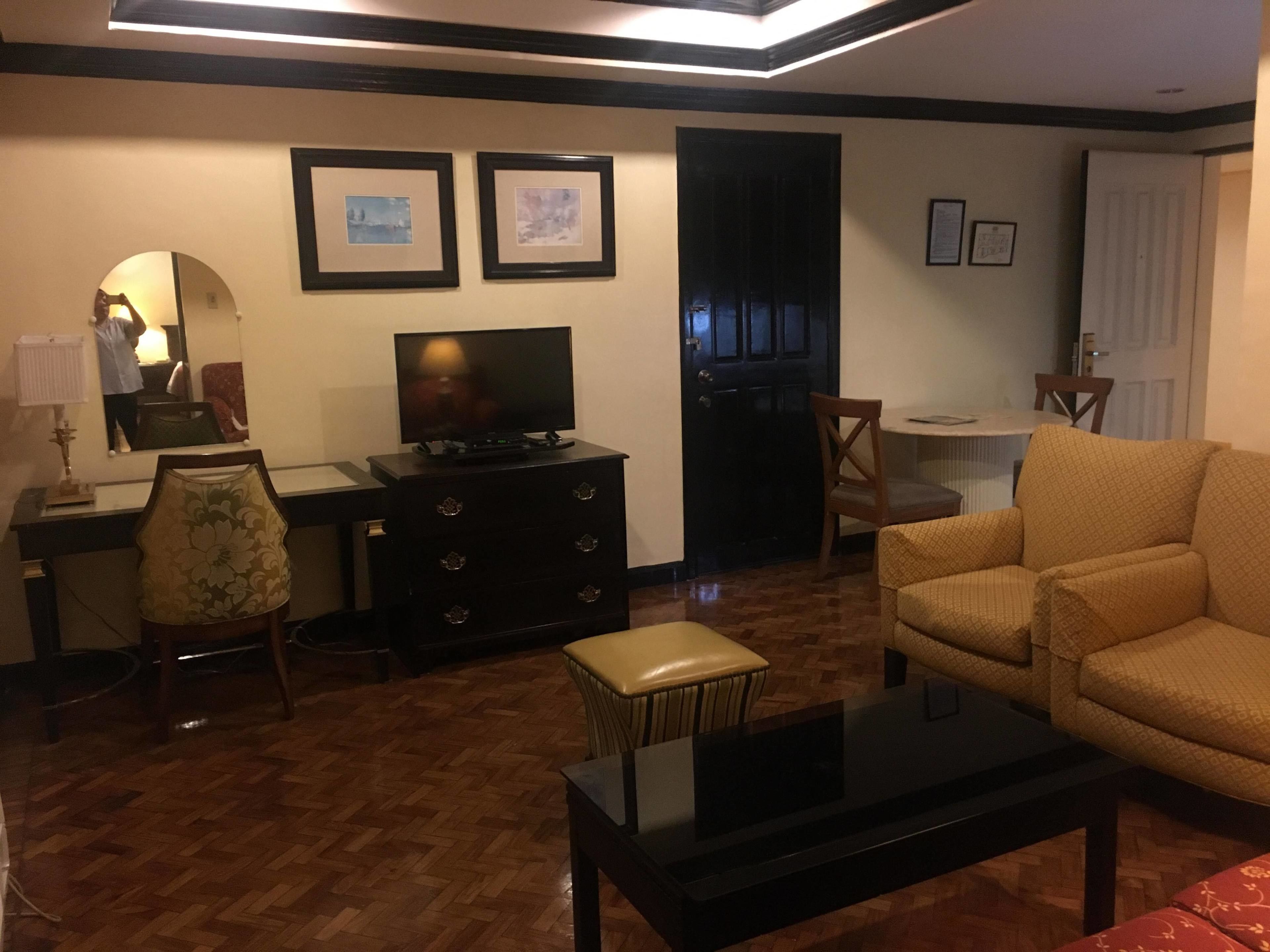 A living room with a television, a sofa, a coffee table, and a dining area with a chair and table.