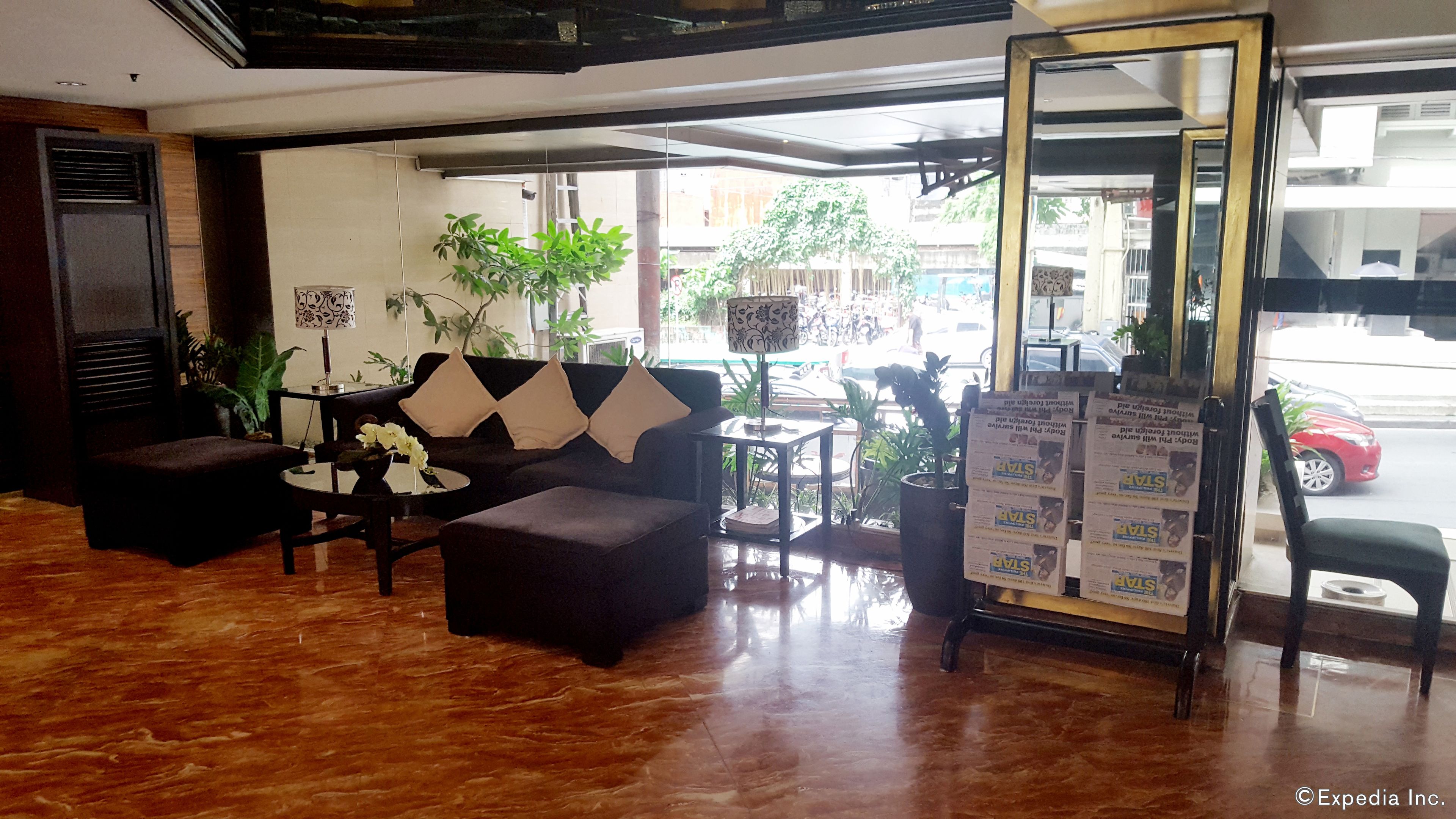 A hotel lobby with a sofa, coffee table, and potted plants.