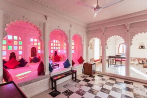 Una habitación tradicional con arcos decorativos, suelo a cuadros y un banco.