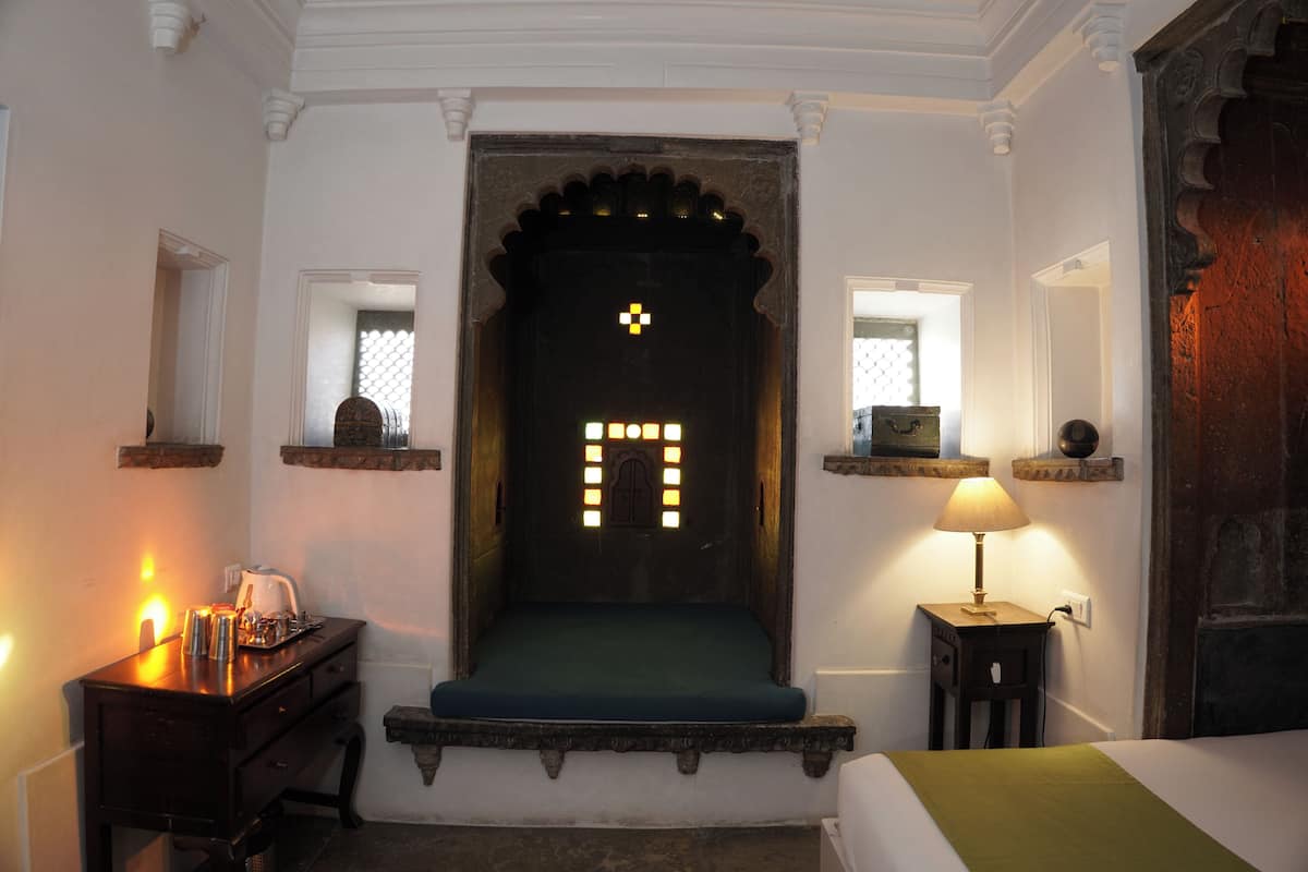 Una habitació amb un llit, un escriptori amb una làmpada i una porta decorativa amb un dibuix de llum.