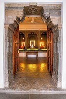 Un arco de piedra ornamentado que da paso a una habitación con un banco e iluminación decorativa.