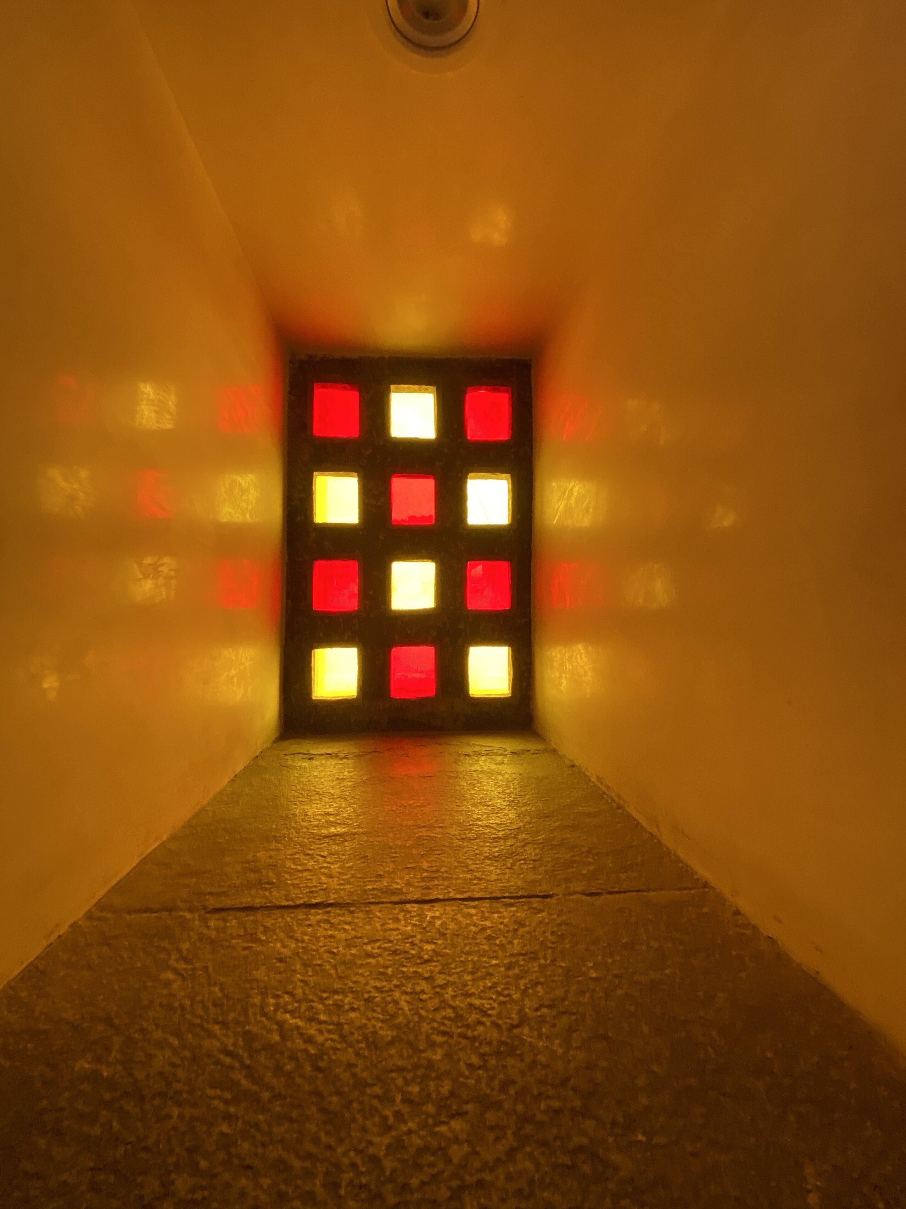 A corridor with a patterned wall and a door at the end.