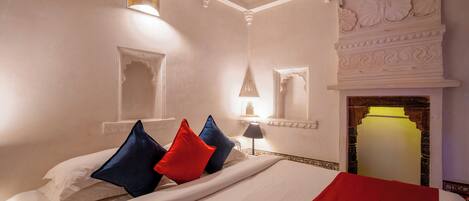 A hotel room with a large bed, a fireplace, and a decorative ceiling.