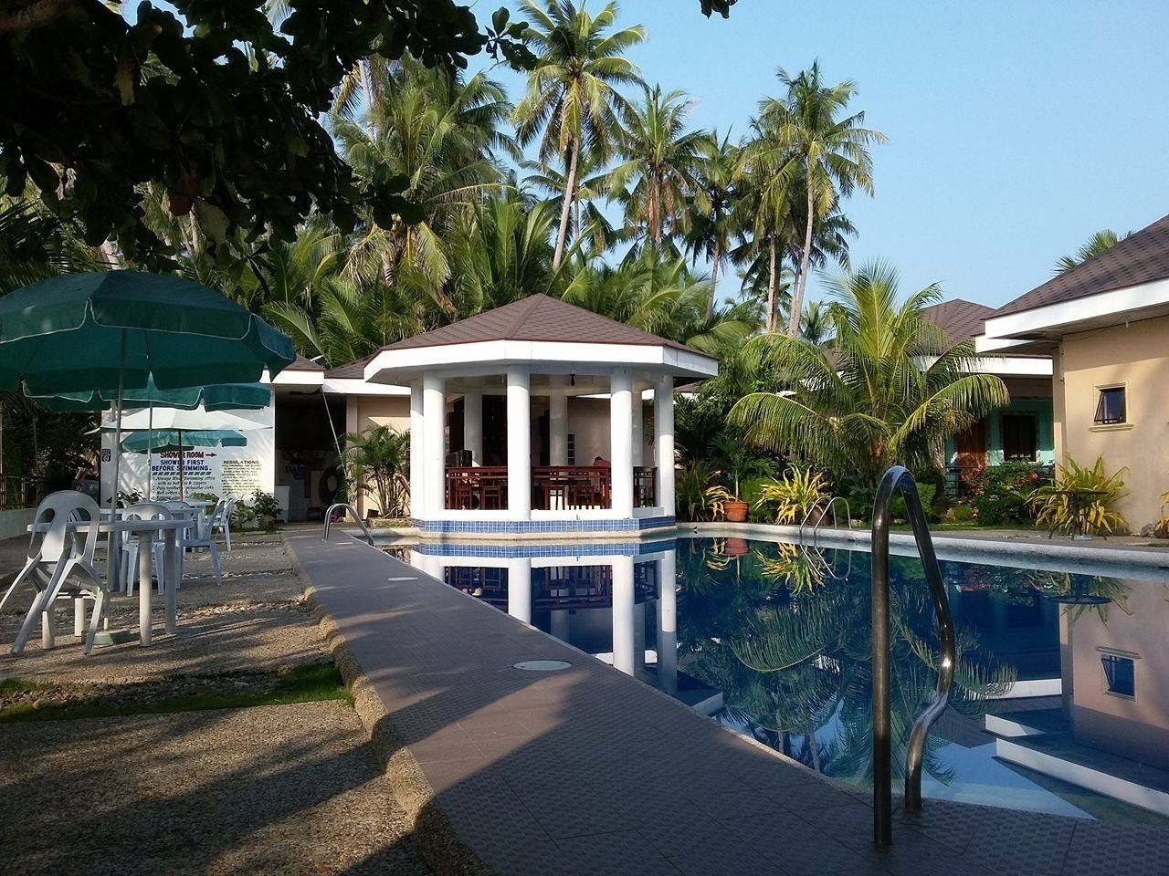 A swimming pool with a covered pavilion, palm trees, and a sign indicating a shower room.