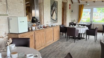 Un ristorante con pareti in pietra, travi in legno e un assortimento di tavoli rotondi e rettangolari.