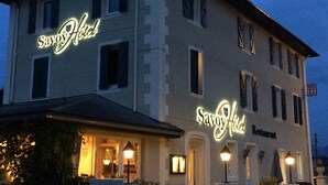 Een gebouw met twee verdiepingen, met de naam Savoy Hotel verlicht op de gevel.