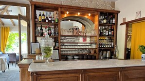 Een bar met houten kasten, drankflessen op planken en een grote glazen container.