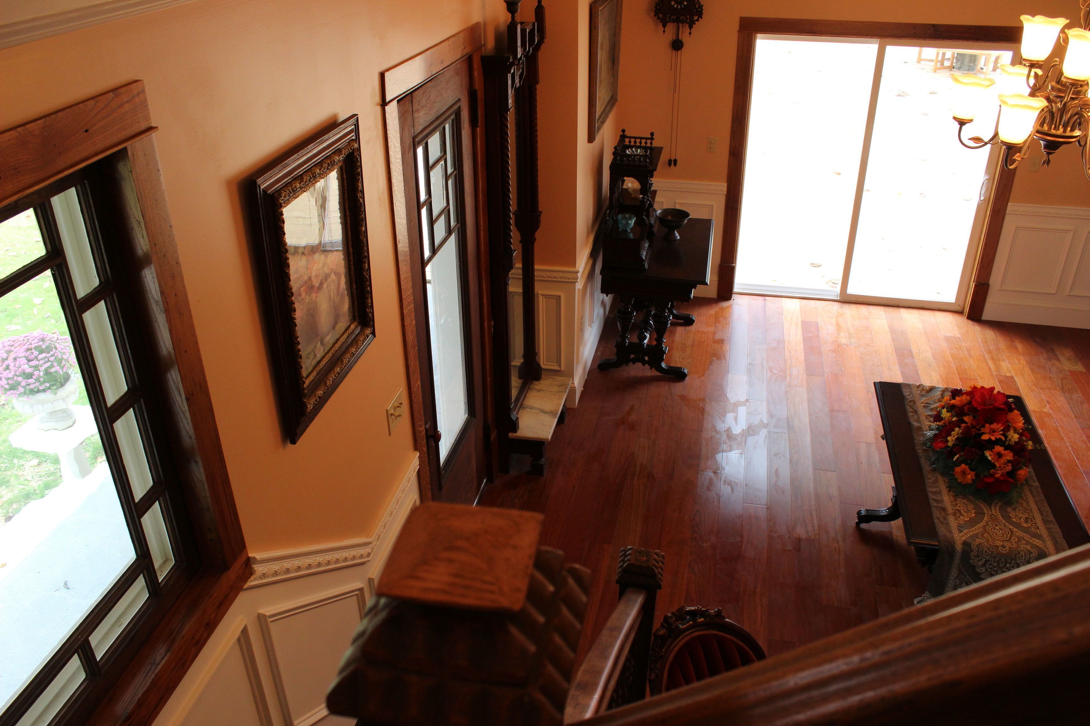 A hallway with wooden flooring, a staircase, and a dining area with a table and chairs.