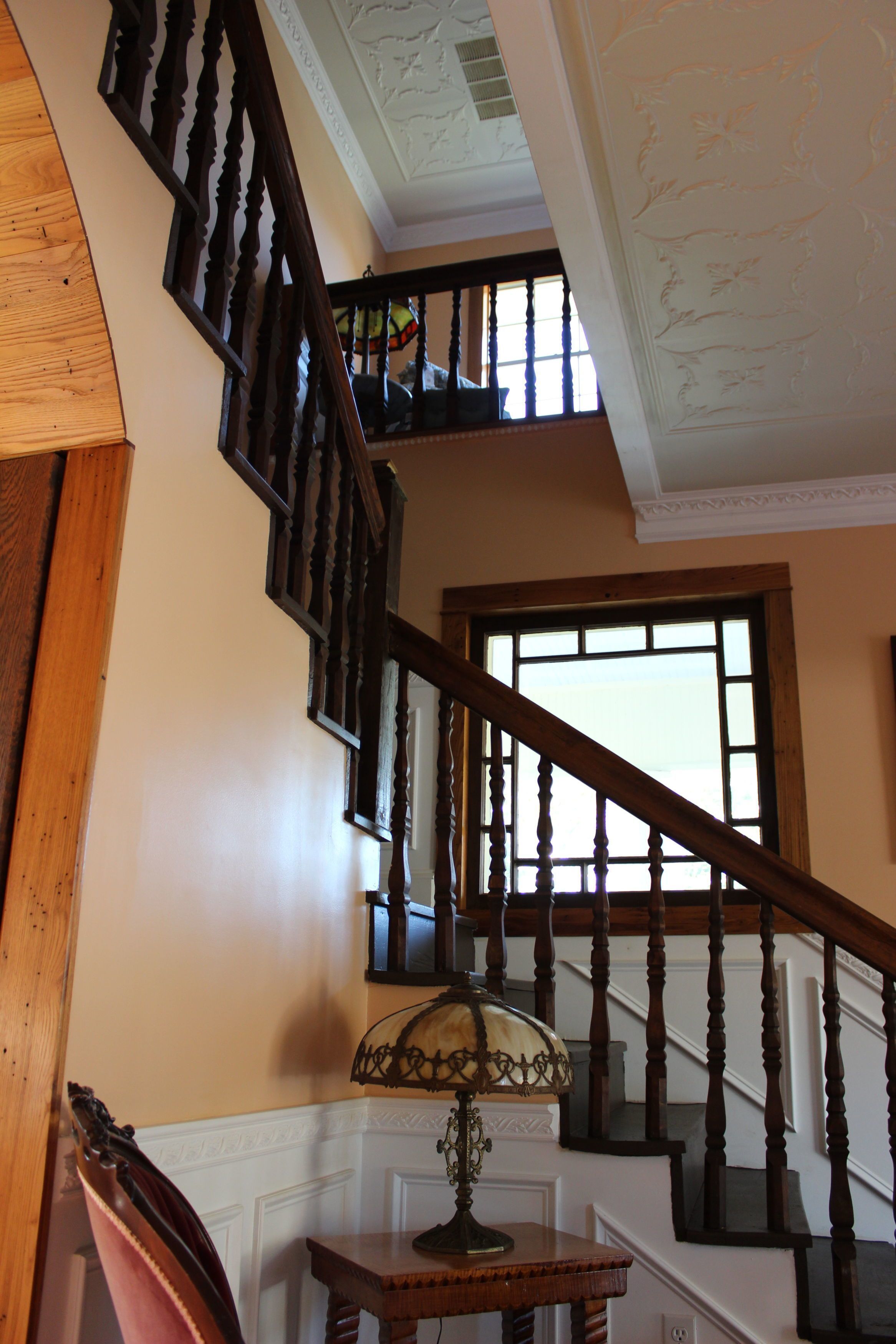 A wooden staircase with a lamp on a table at the bottom.