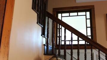 A wooden staircase with a lamp on a table at the bottom.