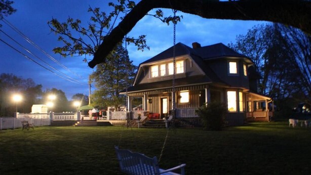 A two-story house with a porch, a swing, and a well-lit front yard at dusk. - Millsap-baker Estate (Damascus)