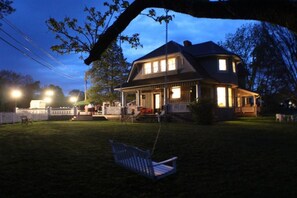A two-story house with a porch, a swing, and a well-lit front yard at dusk. - Millsap-baker Estate (Damascus)