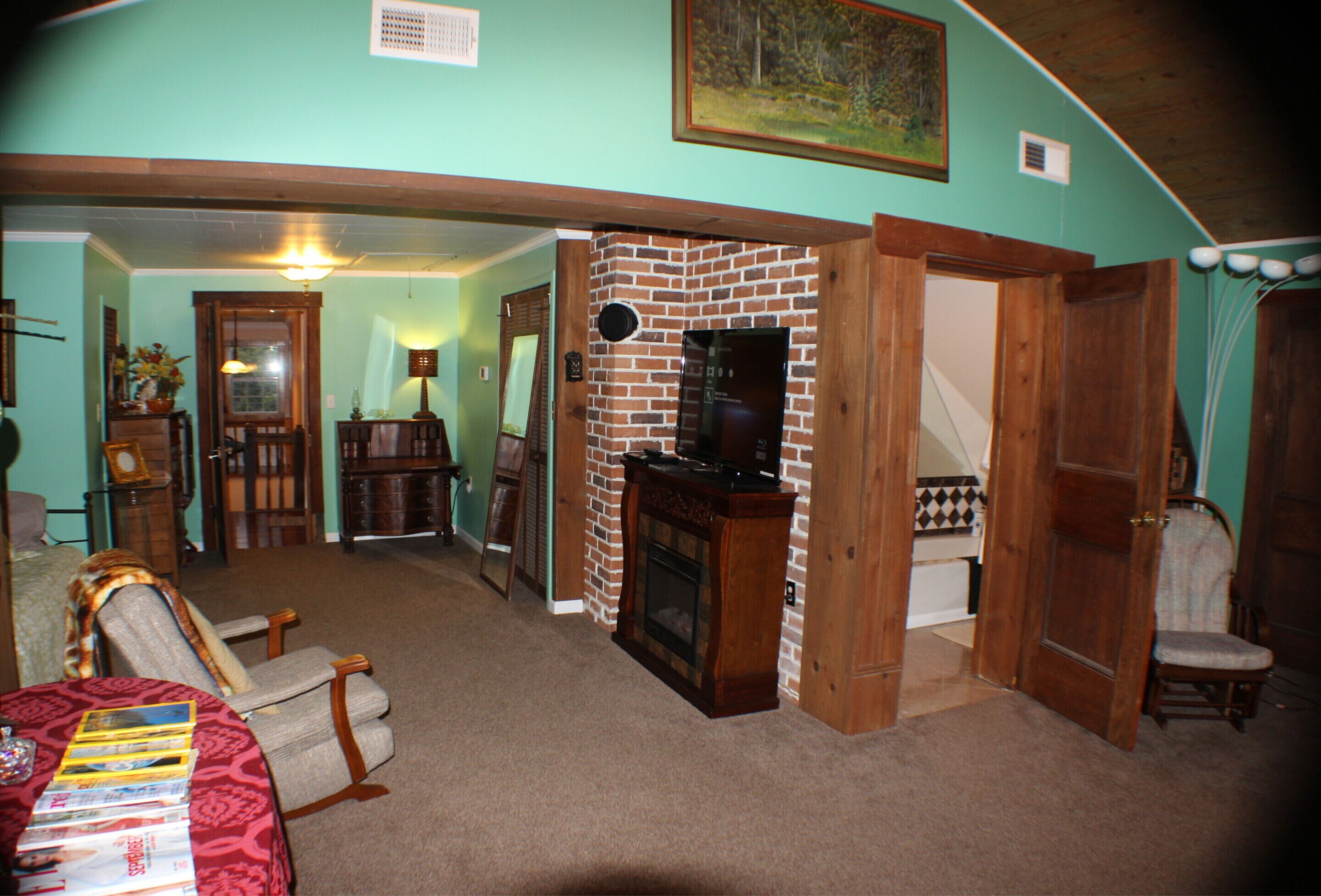 A living room with a fireplace, a dining area, and a staircase leading to another level.