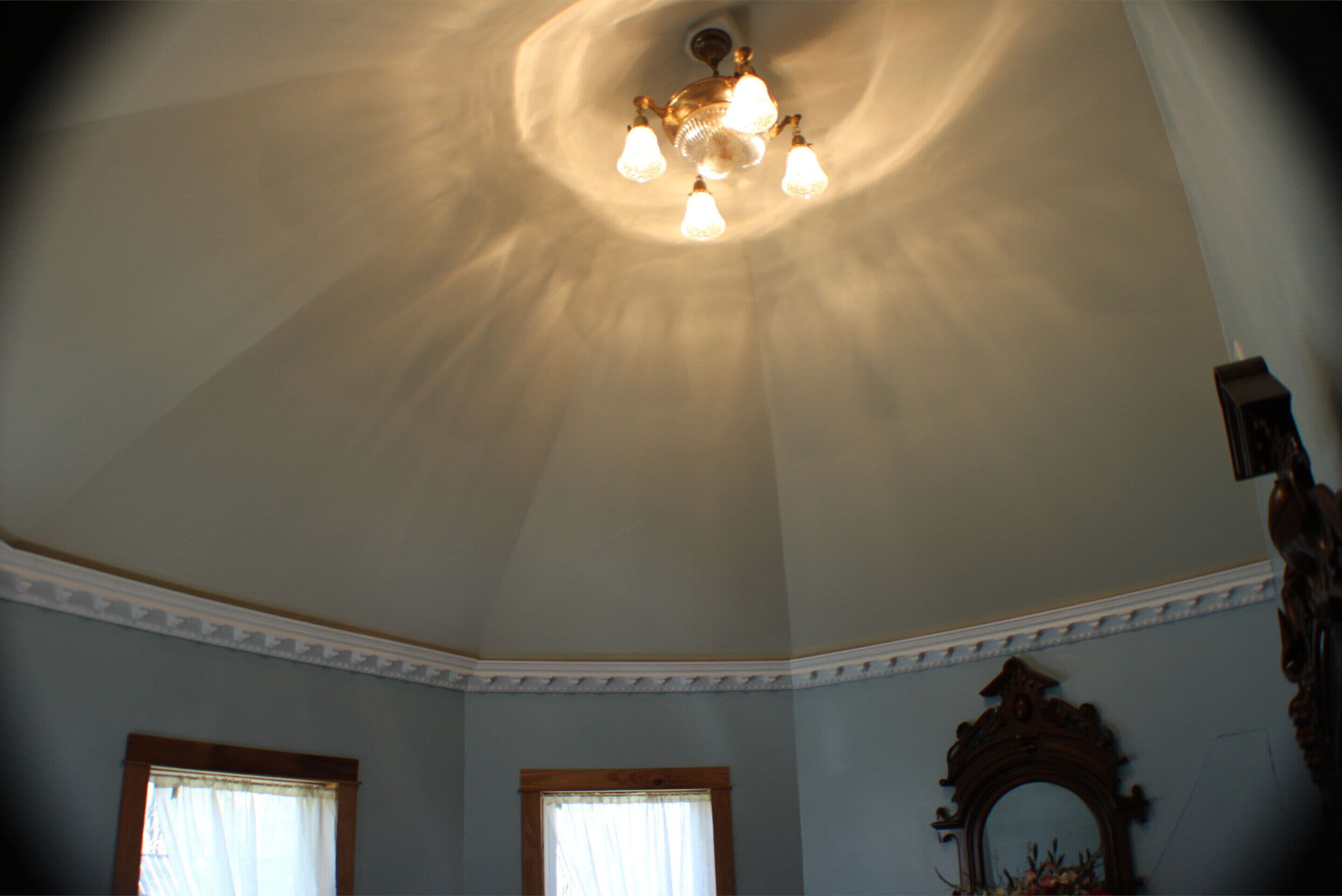 A room with a high ceiling, a chandelier, and a large mirror.