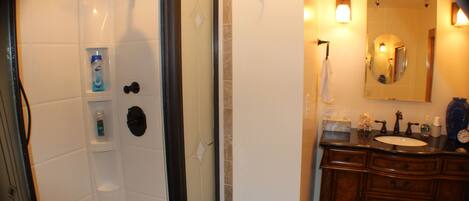 A bathroom with a shower, a sink, and a mirror.