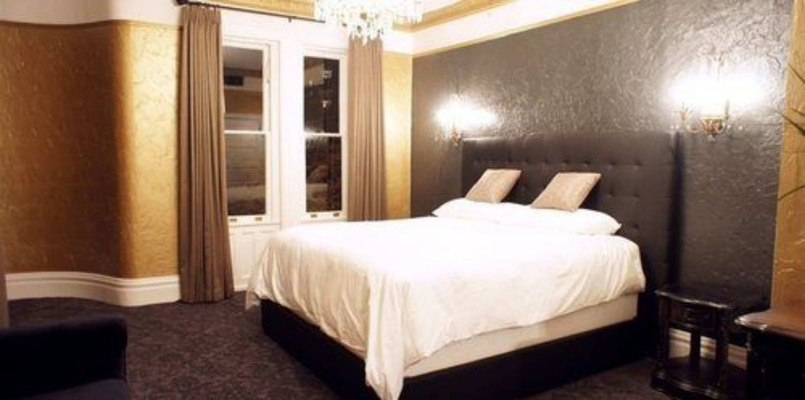 Een hotelkamer met een groot bed, een kledingkast en een kroonluchter.