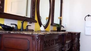 A bathroom with a wooden vanity, a mirror, a towel rack, and a potted plant.